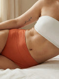 Menstruatie ondergoed oranje, close-up van gedragen huggster brief in een lifestylebeeld op bed