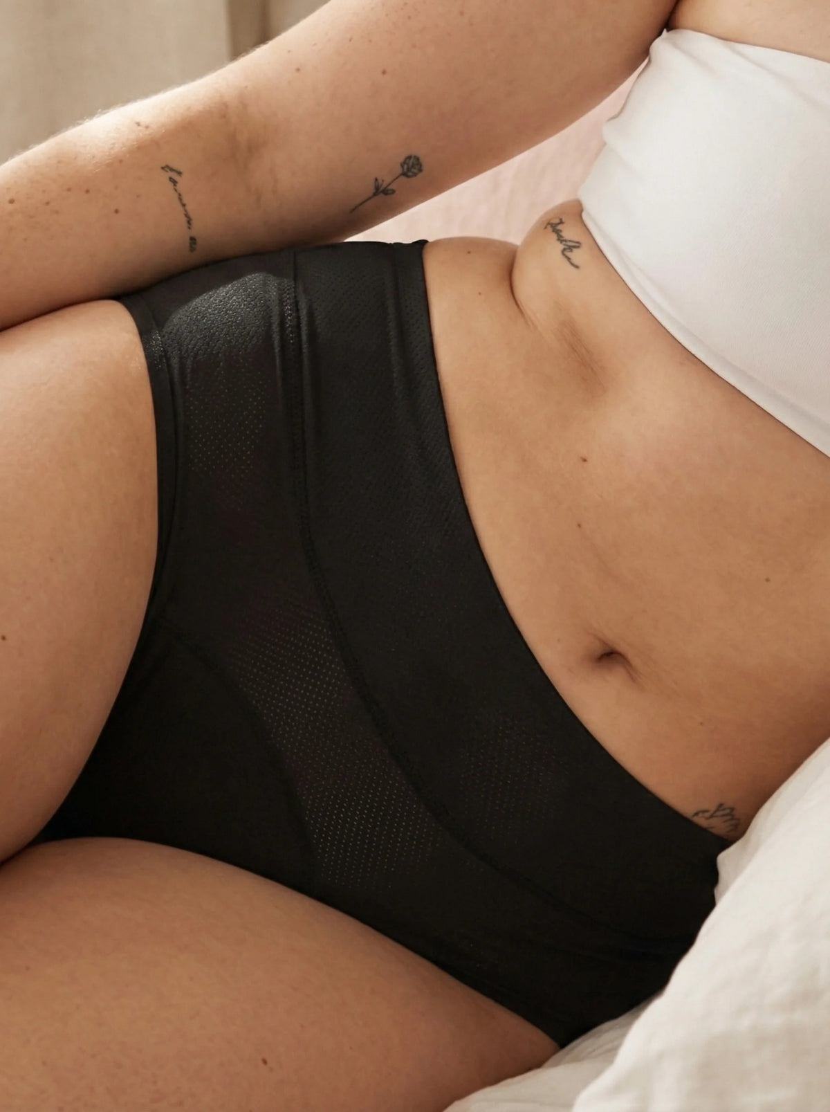Menstruatie ondergoed zwart, close-up van gedragen classic brief in een lifestylebeeld op bed